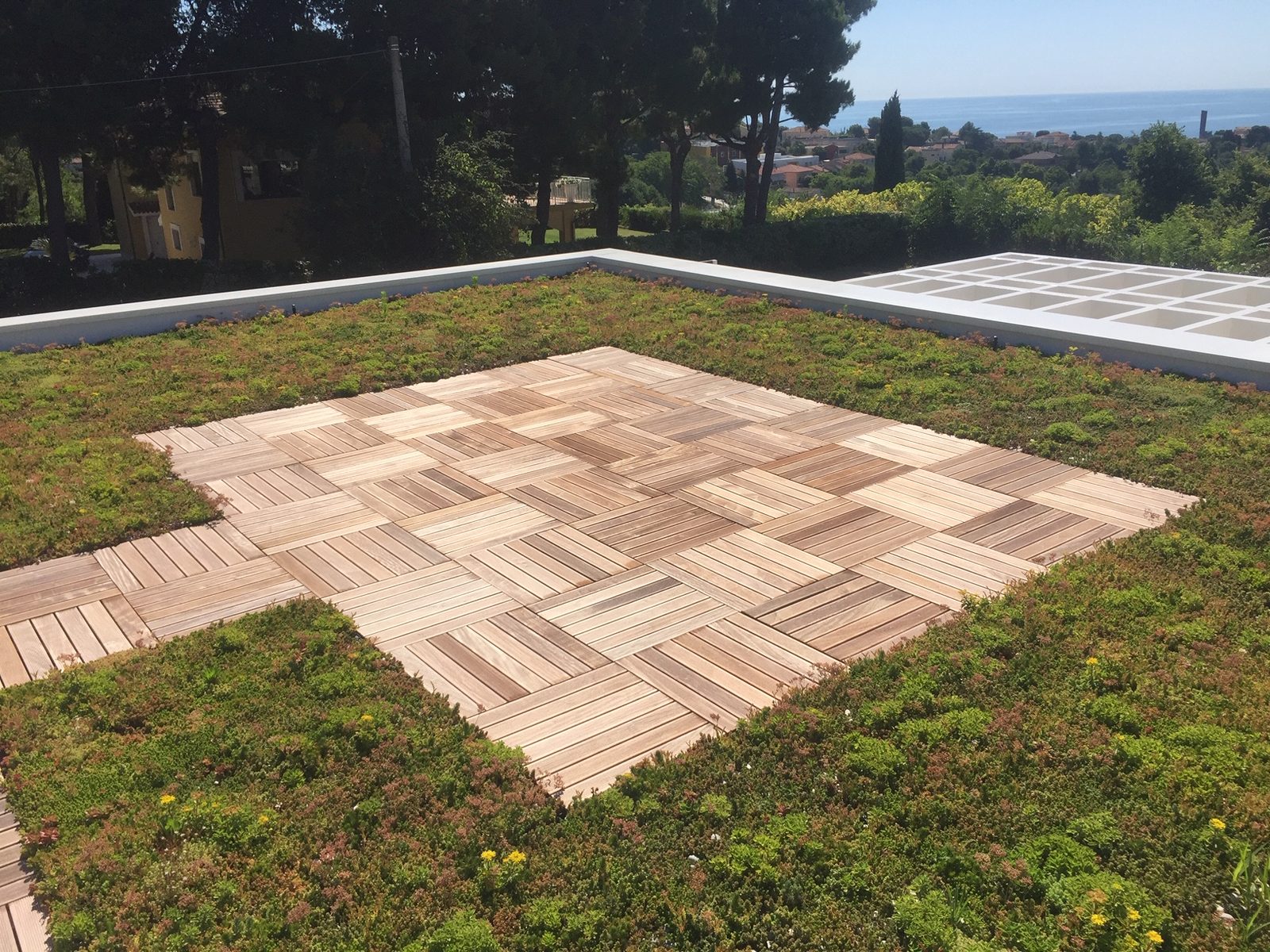 Tetto verde della casa in legno di Sirolo con un quadrato di doghe di legno a scacchiera e il mare sullo sfondo